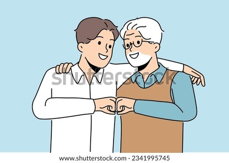 Young son and elderly father hug and bump fists to demonstrate unity and friendship between generations. Man of different ages say together we are strength, calling to be friends for generations