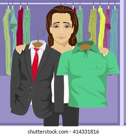 Young thinking man choosing between business suit and shirt in a clothing store