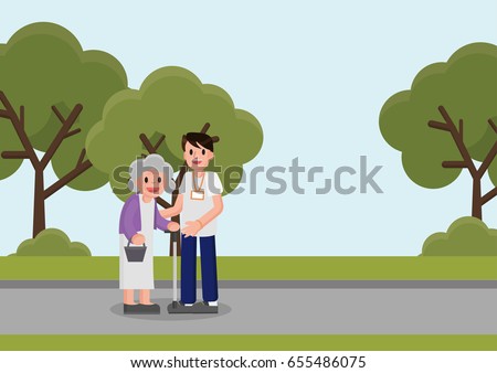 young volunteer man caring for elderly woman in park. Adult man helping and supporting old aged female in garden. Older person standing in front of volunteer.