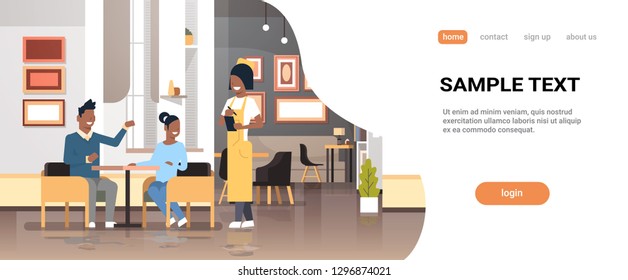 young waiter in uniform taking order from african american couple visitors sitting cafe table service concept modern restaurant interior horizontal flat copy space