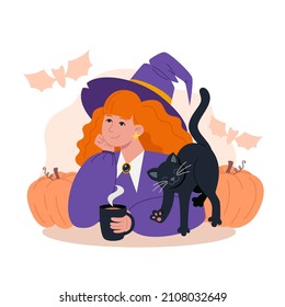 Young witch with red hair and a black cat drinking hot tea