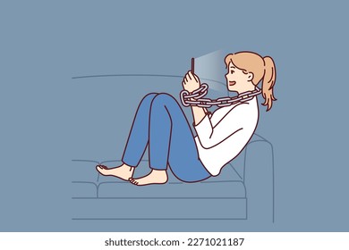 Young woman addicted to mobile phone sitting on sofa with chain around neck. Introverted girl procrastinates using gadgets and suffers from addicted causing loneliness and lack of friends 