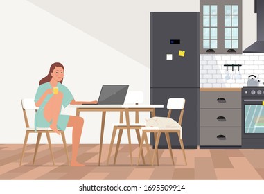 A young woman in a bathrobe with a cup works at a computer in the kitchen.