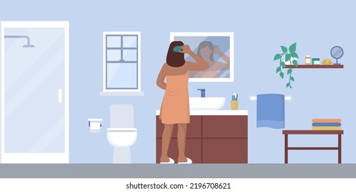 Young woman brushing hair in the bathroom after having a shower, domestic room interior