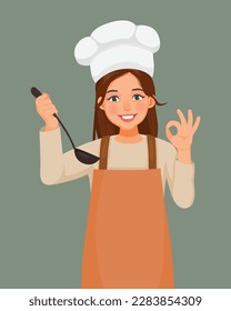 Mujer joven con sombrero de chef con cuchara de cuero de la mano de un delantal que muestra el signo correcto