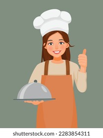 Young woman in chef hat and apron holding a tray showing thumb up