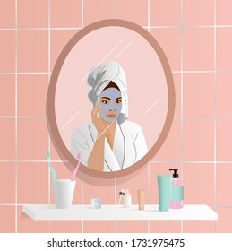 Young woman do her beauty routine. Woman looking in mirror and apply face mask in bathroom. Mirror reflection of skin care.