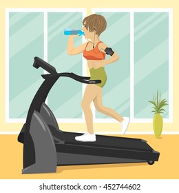 Young woman at gym doing exercise on treadmill with smartphone armband drinking water