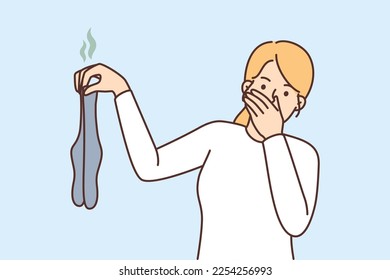 Young woman holding dirty stinky socks in hands disgusted by smell. Girl with smelly stockings irritated repulsed with dirt. Vector illustration. 