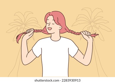 Young woman holding pigtails standing on beach with palm trees for metaphor for inner child. Young happy girl remembers childhood and enjoys life rejoicing at good weather and sunny sky