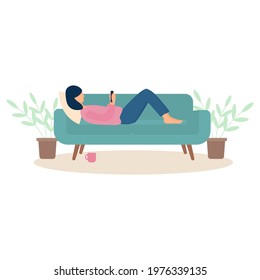 A young woman lies on the couch and looks into a cell phone. Cute girl is resting at home.