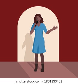 Young woman with microphone makes speech on stage