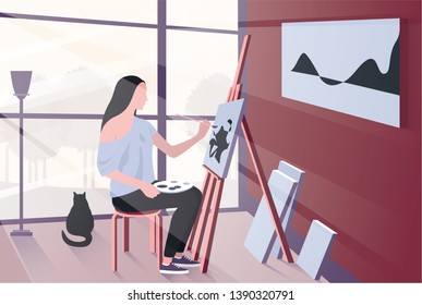 Young woman painting in bright home studio next to her cat