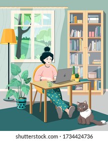 A young woman in pajamas works from home, sitting at a laptop near a bookcase. A fluffy cat sits next to the table. Summer landscape in the window.