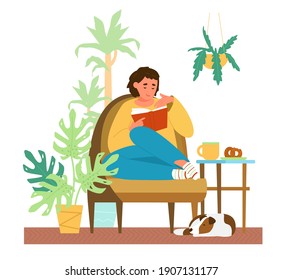 Young Woman Reading A Book At Home In Cozy Armchair Surrounded With Plants Dog Sleeping On The Floor. Self-care And Time For Yourself Concept.