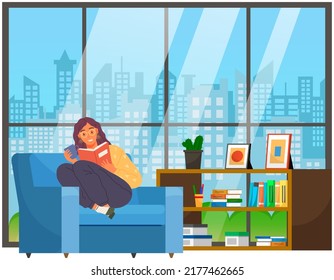 Young woman reading book, sitting on pillows in modern chair. Leisure and education. Relaxation with literature. Girl relaxing at home and drinking coffee. Student reads textbook holds cup in hand