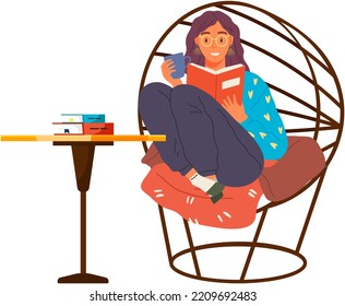 Young woman reading book, sitting on pillows in modern chair. Leisure and education. Relaxation with literature. Girl relaxing at home and drinking coffee. Student reads textbook holds cup in hand