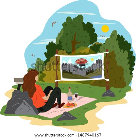 A young woman is relaxing in a park, drinking wine and watching a movie on the street. Street cinema