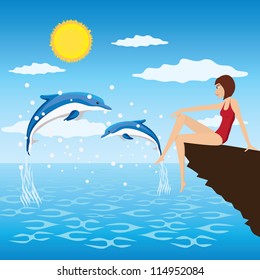 Young woman sit near a sea and look at the jumping dolphins.