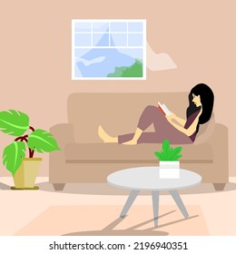 Young woman sitting alone on a couch at home and reading a book.