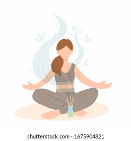 Young woman sitting in lotus pose with aroma diffuser. Aromatherapy and relax. Self care at home.