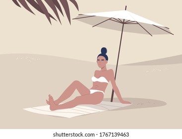 Young woman sitting on the beach under umbrella, summertime vacation, hot tropical climate