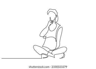 young woman sitting on floor making silence sign with forefinger showing warning