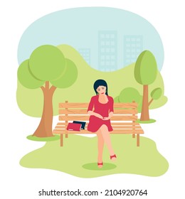 A young woman is sitting on a park bench. There are books nearby. The concept of recreation in the park. 