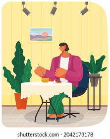 Young woman smiles, rests and spends time in restaurant. Girl at business lunch during break. Person holds spoon, eats, sits next to plants and painting on wall. Lady has nice evening in cafe