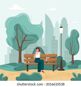Young woman are speaking by phone on a bench in a city park.  Urban city street style, outdoor activity, communications