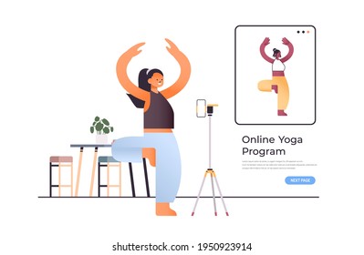 young woman standing in asana pose while watching online video training program with yoga teacher workout concept