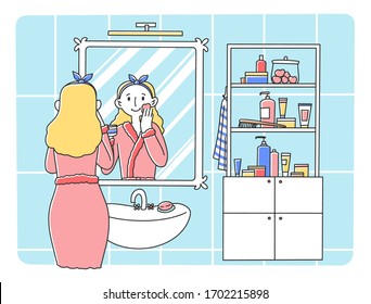 Young woman standing in front of mirror flat vector illustration. Colorful cartoon lady in bathroom washing face skin in morning. Skincare and hygiene concept