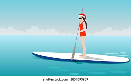 Young woman standing on sup board in Christmas costume