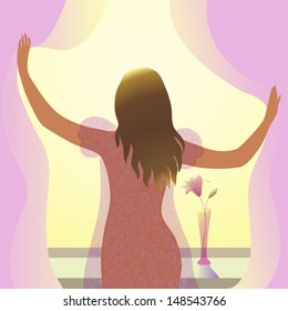 young woman stands near the window in the morning in the rays of the sun