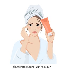 A young woman with a towel on her head holds a cream in her hand. It uses a cosmetic product. Women's face in a cosmetic mask. Skin care banner. The concept of skin care. beauty skin female face