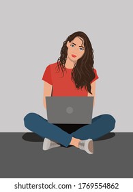 Young woman working on laptop computer while sitting on the floor with legs crossed isolated over gray background
