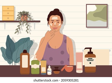 young women doing night skincare routine in bathroom, applying moisturizer cream to her face, many skincare product in front of her