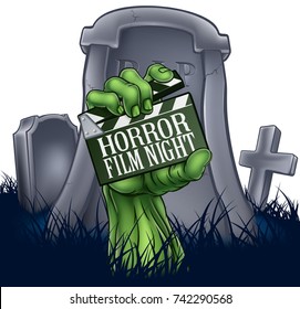 A zombie or Halloween monster hand coming out of a grave holding a movie clapper board. Reading horror film night advertising a scary cinema event or festival screening