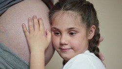a little girl hugs her mother belly. happy family kid pregnancy newborn dream concept. the daughter sent her ear to the belly of the pregnant mother listens to the thrusts of the newborn