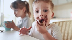 children eat chocolate. dirty little baby kids in lifestyle the kitchen eating chocolate in the morning. happy family eating sweets kid dream concept. baby dirty face eating chocolate cocoa