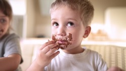 children eat chocolate. dirty little baby kids in the kitchen eating chocolate in the morning. happy family lifestyle eating sweets kid dream concept. baby dirty face eating chocolate cocoa