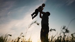 father playing with son in the park. happy family kid dream concept. father throws baby up silhouette in summer at sunset. parent and child play lifestyle toss up silhouette outdoors in the park