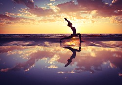 silhouette of woman practicing yoga on the beach at sunset 