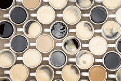 Conceptual image of regimented rows of coffee mugs lined up in straight rows with their handles facing the same direction like coffee soldiers, overhead view with black, espresso, latte and cappuccino