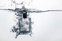 perfume bottle dropped into water on a white background