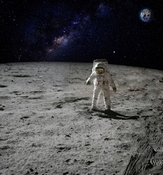 An astronaut walking on the surface of the moon with earth on the background. Elements of this image furnished by NASA.