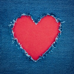 Red heart shape for copy space torn from blue denim jeans fabric, romantic love concept background