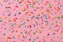trendy pattern of colorful sprinkles over pink background, decoration for cake and bakery
