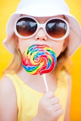 Adorable little girl with lollipop over colorful background