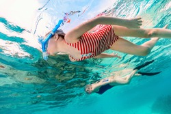 Underwater photo of family mother and daughter snorkeling in a clear tropical water at coral reef